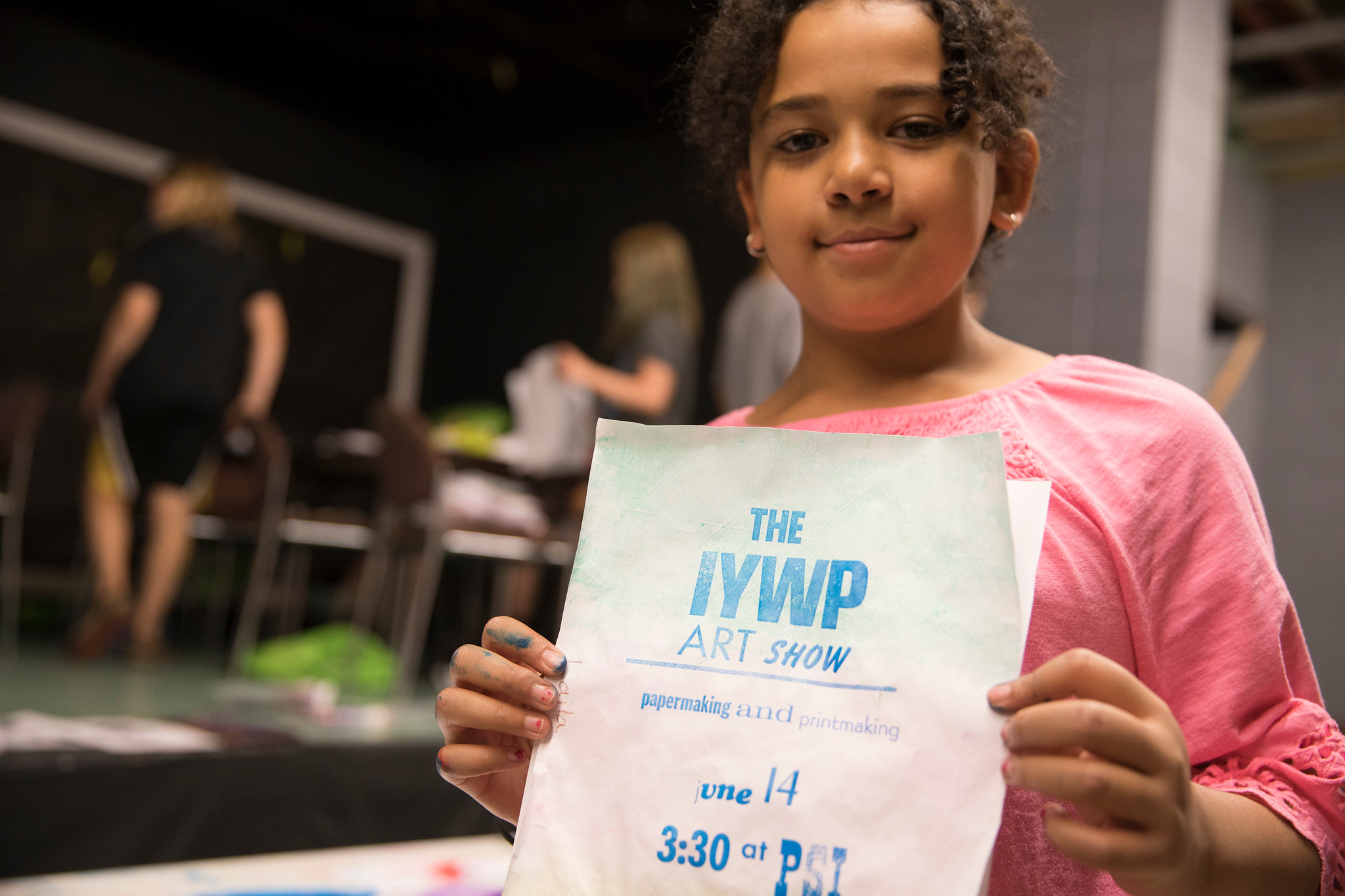 A young member of the IYWP holding an example of work she created in the program.