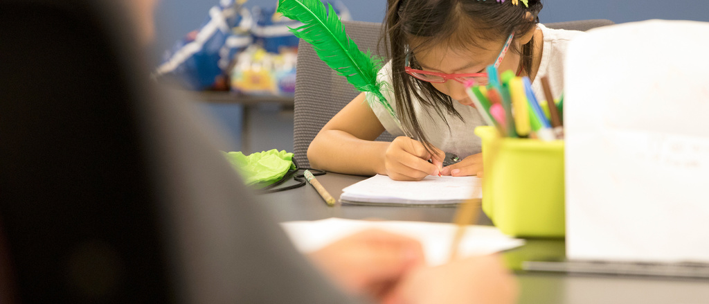 A young girl writing in her journal during the IYWP Summer Camp