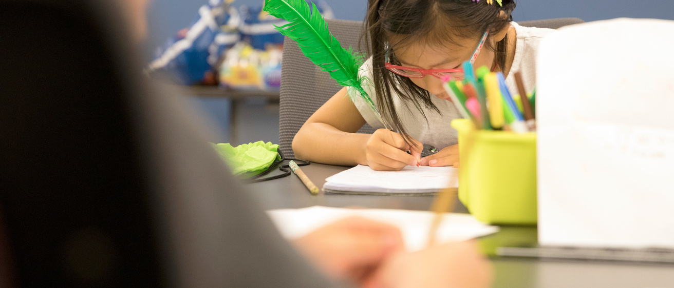 A young girl writing in her journal during the IYWP Summer Camp